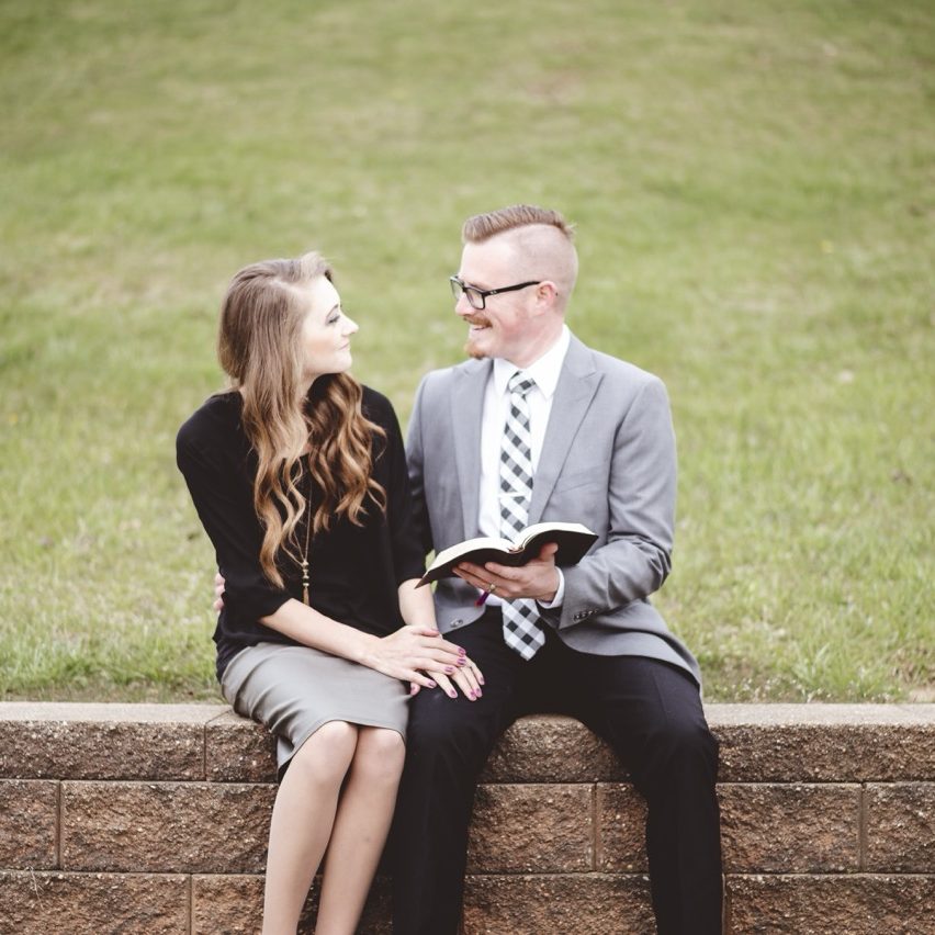 A shallow focus shot of a couple talking and enjoying each others company while sitting in a garden